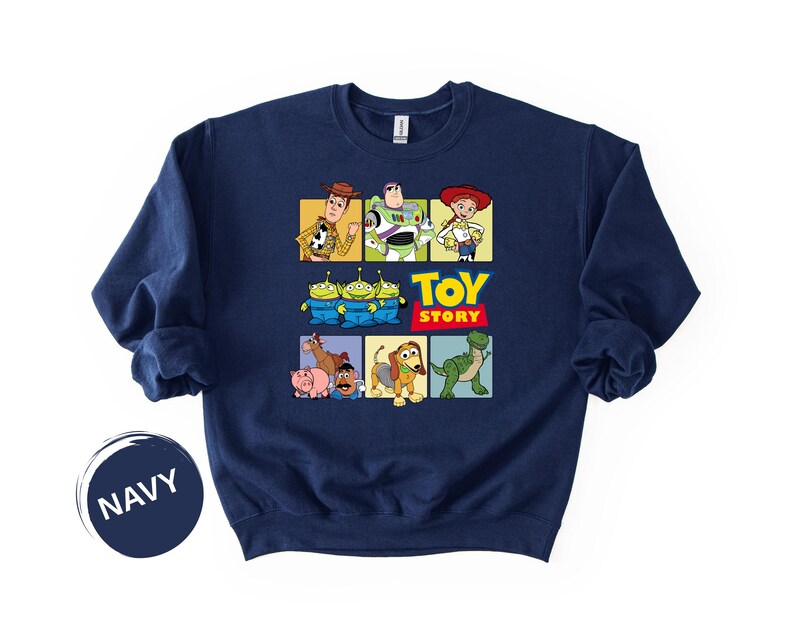 May include: A navy blue crewneck sweatshirt featuring a graphic print of Toy Story characters including Woody, Buzz Lightyear, Jessie, the Aliens, Bullseye, Hamm, Mr. Potato Head, Slinky Dog, and Rex, with the yellow and red Toy Story logo text.