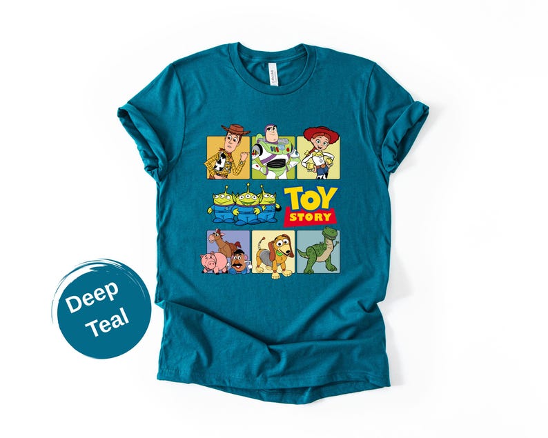 May include: A deep teal short-sleeve t-shirt featuring a graphic print of Toy Story characters including Woody, Buzz Lightyear, Jessie, the Aliens, Hamm, Mr. Potato Head, Slinky Dog, and Rex, with the Toy Story logo printed in yellow and red.