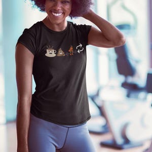 May include: Black t-shirt with a humorous graphic. The graphic includes a coffee cup, a pile of poop, a weightlifter, and a recycling symbol. The shirt is made of a soft material and has a crew neck.