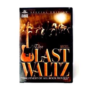 Puede incluir: Una caja de DVD de la edición especial de The Last Waltz, con una guitarra eléctrica dorada a la izquierda y la silueta de una multitud en un concierto frente a una luz brillante. El texto dice The Last Waltz y The Finest of All Rock Movies.