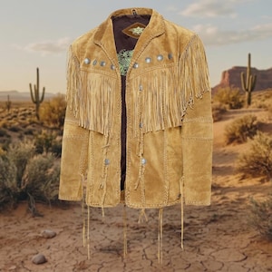 May include: A tan suede jacket featuring long fringe detailing across the chest and sleeves. The jacket is adorned with silver-toned circular metal concho accents along the front yoke and down the center, with braided leather trim and long hanging leather ties.