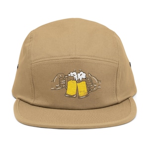 Può includere: Cappellino a cinque pannelli color beige con visiera curva. Il cappellino presenta un ricamo di due boccali di birra gialla che si toccano, tenuti da mani, con schiuma bianca. Un accessorio casual.