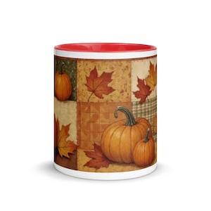 May include: A ceramic mug with a bright red interior and rim. The exterior features a patchwork-style design with various autumn-themed illustrations, including orange pumpkins and multicolored maple leaves in shades of red, gold, and brown.