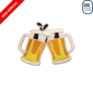 May include: Embroidered patch featuring two beer mugs clinking together. The mugs are filled with golden beer and topped with white foam. The patch has a white border and is labeled "NEW ARRIVAL".