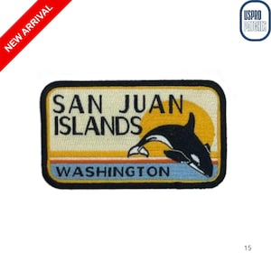 May include: Embroidered patch featuring a black and white orca leaping in front of a yellow sun. The patch reads "SAN JUAN ISLANDS WASHINGTON" in black text on a tan background with a black border. A red "NEW ARRIVAL" banner is in the upper left.
