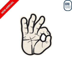 May include: A white patch with a black outline of a hand making the "OK" gesture. The patch has a textured appearance. A red banner in the upper left corner reads "NEW ARRIVAL". The USPRO PATCHES logo is in the upper right corner.