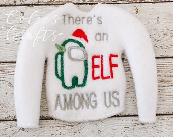 以下が含まれることがあります： 白いフェルトのセーター、長袖。 「There's an ELF AMONG US」の文字がグレーと赤で刺繍されています。 サンタ帽をかぶったAmong Usのキャラクターが前面に刺繍されています。 このセーターはエルフ用にデザインされています。