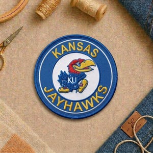 May include: A rustic wooden sign with the text "Welcome" in a handwritten style. The sign is painted white with a distressed finish, and features a decorative floral element in the corner. The background is a blurred image of a wooden surface.