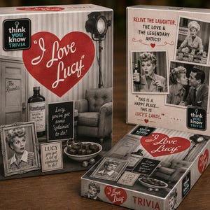 May include: Three boxes of I Love Lucy trivia games featuring black and white imagery of the television show. The packaging displays a large red heart, a bottle of Vitameatavegamin, a bowl of chocolates, and quotes like Lucy, you've got some 'splainin' to do!