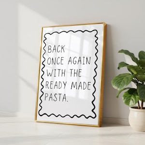 May include: A rectangular wall art print in a thin gold frame featuring a white background with a black wavy border. The text in black, sans-serif font reads: BACK ONCE AGAIN WITH THE READY MADE PASTA. The design is centred within the frame.