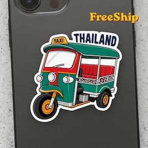 May include: A die-cut sticker featuring a green and red Thai tuk-tuk with a yellow taxi sign on the roof. The vehicle has three black wheels with orange centers and red interior seating. The word THAILAND is printed in dark blue capital letters.