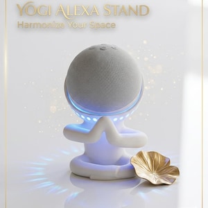 Könnte beinhalten: Ein weißer Yogi Alexa-Ständer mit einem grauen Lautsprecher, der in Form einer Person in einer Yoga-Pose gestaltet ist. Der Ständer hat blaue Akzentbeleuchtung und enthält ein goldfarbenes Lotusblatt. Der Text auf dem Bild lautet "Yogi Alexa Stand" und "Harmonize Your Space."