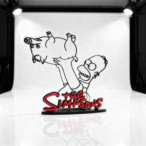 Può includere: Una scultura in filo nero di Homer Simpson che tiene un maiale, con le parole "The Simpsons" in rosso e nero. La scultura è su una base nera e su uno sfondo bianco.