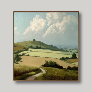 May include: A framed landscape painting depicts a rolling green hill under a cloudy sky. The painting features a winding path through fields of varying shades of green and tan. The artwork is framed in a simple, light brown wooden frame.