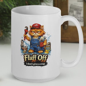 K&ouml;nnte beinhalten: Wei&szlig;e Keramiktasse mit einem Cartoon-Katzenklempner, der einen Schraubenschl&uuml;ssel h&auml;lt, blaue Latzhosen und eine rote Kappe tr&auml;gt. Die Tasse hat den Text "Fluff Off" und "I don't give a crap." Ein humorvolles Design.