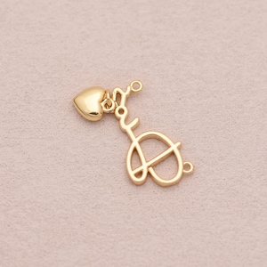 Könnte beinhalten: Ein goldfarbener Metallanhänger mit dem in Schreibschrift geschriebenen Wort 'love' und einem kleinen, glatten Herz an der Oberseite. Der Anhänger verfügt über zwei kleine kreisförmige Ösen an den Enden zur Befestigung und hat eine polierte Oberfläche.