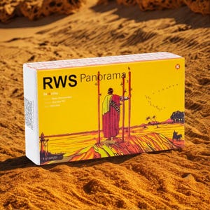 May include: A rectangular box with the text "RWS Panorama" and an illustration of a person on a hill. The box has a yellow background with the words "3 of WANDS" at the bottom. The box is sitting on a sandy surface.