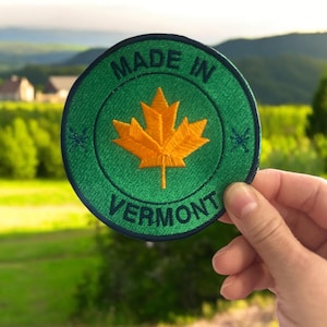 May include: A green and blue circular patch with the text "Made in Vermont" and a yellow maple leaf in the center.