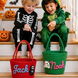Puede incluir: Una cesta de cuerda roja con el nombre Jack en azul y un parche de esqueleto, y una cesta de cuerda verde con el nombre Noah en rosa y un parche de monstruo blanco. Ambas cestas tienen dos asas y sirven para recoger objetos en Halloween.