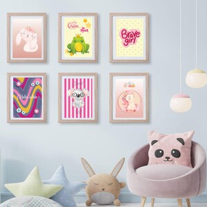 Könnte beinhalten: Ein Set aus sechs gerahmten Wandbildern mit Illustrationen eines Hasen, eines Frosches mit dem Text Queen Diva, eines Herzens mit Brave girl, Wellenmustern mit Habs schön, eines Koalas mit Cool und eines Einhorns mit Be brave, sowie Plüschkissen.