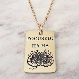 May include: A white ceramic mug with a black handle and the text "But First, Coffee" in a bold, black font. The mug is filled with a dark liquid, likely coffee, and sits on a light-colored surface.