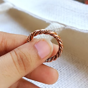 Könnte beinhalten: Ein kupferfarbener Ring mit einem gedrehten Seildesign über das gesamte Band. Das Metall hat ein warmes, metallisches Finish mit sichtbarer Textur entlang der gedrehten Segmente. Der Text Silver925ringshop ist in kleinen schwarzen Buchstaben aufgedruckt.