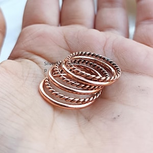Könnte beinhalten: Ein Set aus drei kupferfarbenen Ringen, die jeweils eine gedrehte, seilartige Textur aufweisen. Die Ringe sind übereinander gestapelt und haben eine metallische Oberfläche. Der Text Silver925ringshop ist auf der linken Seite der Ringe sichtbar.