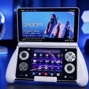 May include: A white handheld gaming console with a dual-screen design. The top screen displays a PlayStation Portable library interface with character art, while the bottom screen shows a grid of app icons, a directional pad, two joysticks, and buttons.
