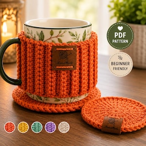 Puede incluir: Una taza de cerámica con patrón de hojas verdes, envuelta en una funda de ganchillo naranja acanalada con una etiqueta de cuero marrón que dice HandMade. Un posavasos de ganchillo naranja a juego se encuentra al lado. Texto: PDF PATTERN, BEGINNER FRIENDLY.