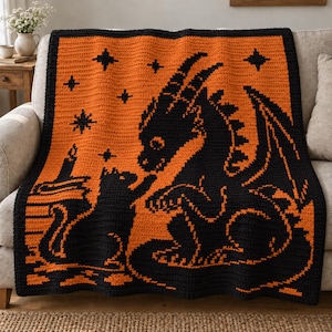 May include: A rectangular crochet blanket featuring a black and orange colour scheme. The design displays a large black dragon facing a black cat sitting on a stack of books next to a lit candle, all set against an orange background with stars.