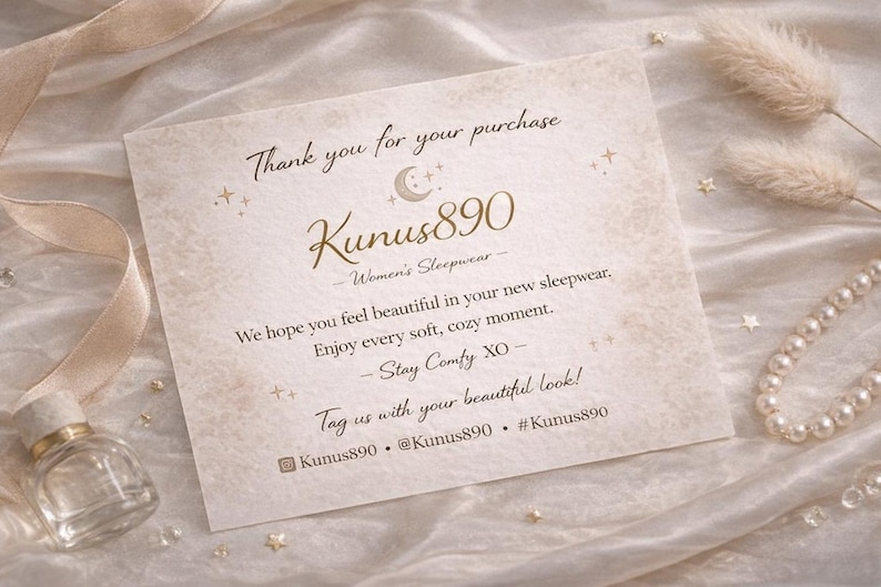 May include: A cream-colored card with gold text that reads "Thank you for your purchase" and "Kunus890 Women's Sleepwear." The card is decorated with small stars and a crescent moon. A small perfume bottle and a pearl necklace are also visible.