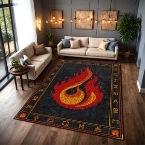 May include: A rectangular area rug with a black background and a large, stylized flame design in red and yellow. The rug has a border with geometric symbols and a gold frame. The rug is placed in a living room with beige sofas and wooden floors.