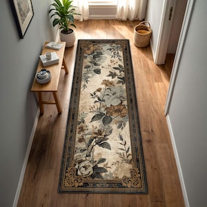 May include: A rectangular floral runner rug with a dark border and ornate corner designs. The rug features a cream background with large, detailed flowers in shades of brown, gray, and white, creating a vintage aesthetic. The rug is placed in a hallway.