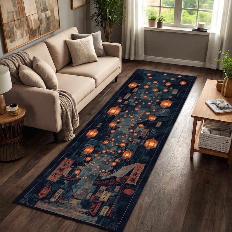 Puede incluir: Una alfombra larga y rectangular que representa una escena callejera nocturna con linternas naranjas brillantes. La alfombra tiene un fondo azul oscuro con ilustraciones detalladas de edificios y texto japon&eacute;s. Las linternas est&aacute;n dispersas por el dise&ntilde;o.