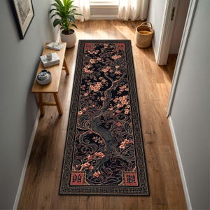 May include: A long, rectangular black rug featuring a floral tree design. The tree has pink blossoms and a dark grey trunk. The rug has a decorative border and Chinese characters at each end. Suitable for a hallway or entryway.