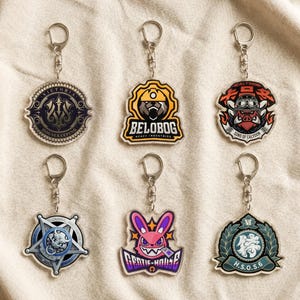 May include: Six acrylic keychains featuring various circular and shaped designs. The emblems include Victoria Housekeeping, Belobog Heavy Industries, Sons of Calydon, a star-shaped Criminal Investigation badge, Gentle House with a pink rabbit, and H.S.O.S.6.