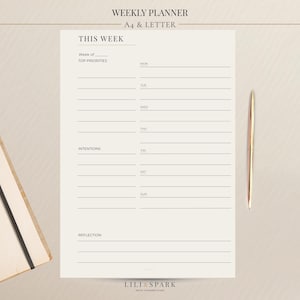 May include: A weekly planner with the text "WEEKLY PLANNER" and "THIS WEEK". The planner has sections for top priorities, intentions, and reflection. A gold pen and a notebook with a black elastic band are also visible.