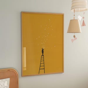 May include: A framed art print featuring a silhouette of a person on a ladder reaching for stars against a mustard yellow background. The artwork has a minimalist style with a wooden frame, suitable for home decor.