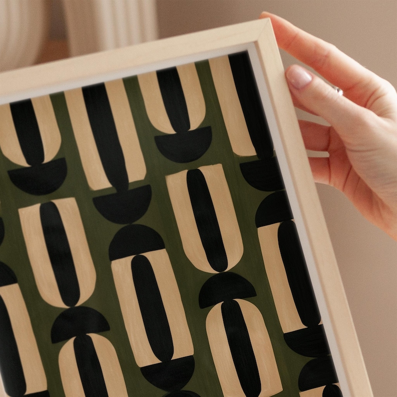African-inspired geometric wall art featuring repeating abstract black and beige shapes against a deep olive green background.