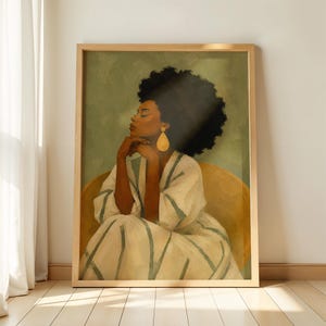 May include: A framed wall art print featuring a painting of a person with dark skin and voluminous curly hair, wearing a white robe with green stripes and a large gold teardrop earring, seated in a rounded chair against a sage green background.