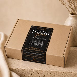 May include: A rectangular brown cardboard shipping box featuring a black rectangular sticker on the lid. The sticker displays the text: The Riley Roost THANK you FOR YOUR ORDER, The Riley Roost, I really appreciate your support & hope you enjoy!, PROUDLY LAID IN VERNAL, UTAH, Find us on Facebook! @TheRileyRoost.