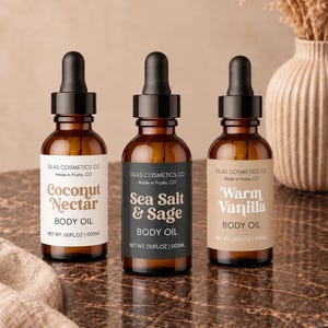 May include: Three amber glass bottles with black dropper caps, each containing body oil. The labels read Silas Cosmetics Co, Made in Fruita, CO, and feature the scents Coconut Nectar, Sea Salt & Sage, and Warm Vanilla with net weight 00FLOZ | 000ML.