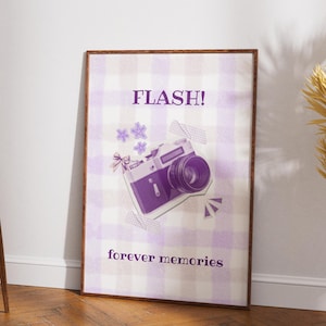 Può includere: Una stampa incorniciata con un motivo a quadri viola e bianchi, raffigurante un'illustrazione di una macchina fotografica vintage. La stampa include le parole "FLASH!" e "forever memories". La fotocamera è raffigurata in viola e bianco, con elementi decorativi.