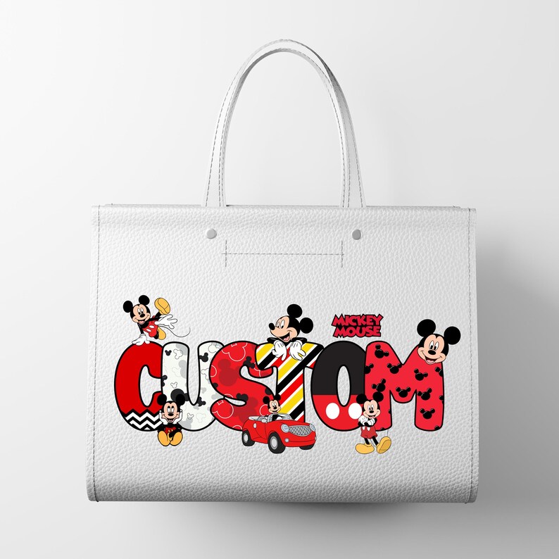 May include: White tote bag with the word "CUSTOM" in large, colorful letters. Mickey Mouse characters are incorporated into the design, with the words "Mickey Mouse" above the letter "M". The bag has two handles.