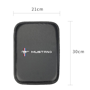Puede incluir: Accesorio de coche negro rectangular con un patrón de fibra de carbono. Presenta la palabra "MUSTANG" en blanco y un logotipo. Mide 21 cm x 30 cm.
