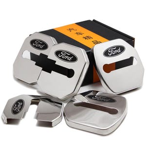May include: A set of five shiny, silver-colored car door lock covers with the Ford logo in black. The covers are in various shapes and sizes, with a black and orange box in the background.