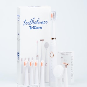 May include: A white electric toothbrush set with the text "teethobrace TriCare" on the box. The set includes multiple brush heads, a charging base, and a small mirror. The toothbrush has rose gold accents.