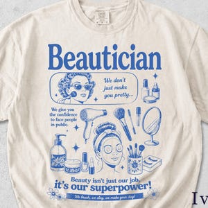 Könnte beinhalten: Elfenbeinfarbenes T-Shirt mit blauem Grafikdesign. Das Design zeigt das Wort "Beautician" über Illustrationen von Schönheitsprodukten und Frauen. Der Text enthält "We don't just make you pretty..." und "Beauty isn't just our job, it's our superpower!"