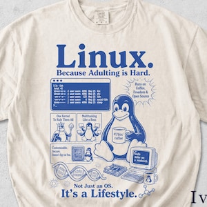May include: An ivory t-shirt featuring blue graphic prints. The text reads Linux. Because Adulting is Hard. It includes a terminal window, a penguin mascot holding a coffee mug labeled #1/bin/coffee, a computer monitor with text, and other icons.