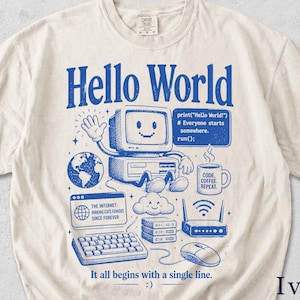 Könnte beinhalten: Ein elfenbeinfarbenes T-Shirt mit einem blauen Grafikdruck eines lächelnden Computer-Charakters, einem Globus, einer Kaffeetasse mit der Aufschrift CODE. COFFEE. REPEAT., einer Wolke, einem Router und einer Tastatur. Text enthält Hello World.